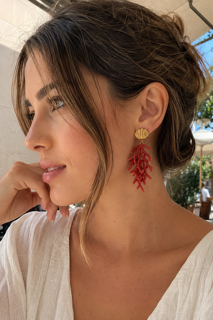 Femme portant les boucles d'oreilles branche de corail rouge et coquillage doré