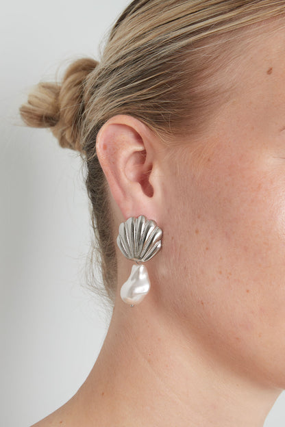 Femme portant les boucles d'oreilles coquille et perle baroque