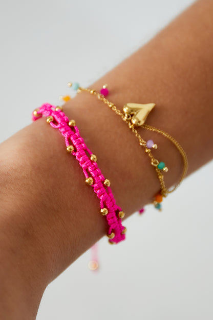 Bracelet cordon rose fluo perles dorées porté au poignet, empilé avec chaîne cœur doré