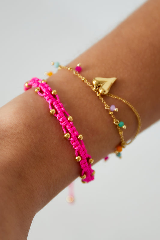 Bracelet cordon rose fluo perles dorées porté au poignet, empilé avec chaîne cœur doré