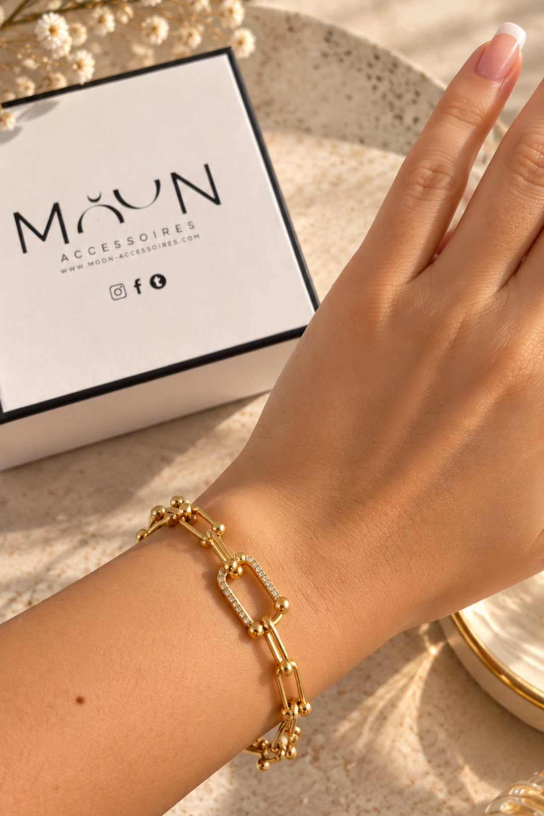 Bracelet doré à maillons allongés et billes porté au poignet avec écrin Moon