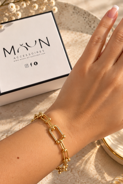 Bracelet doré à maillons allongés et billes porté au poignet avec écrin Moon