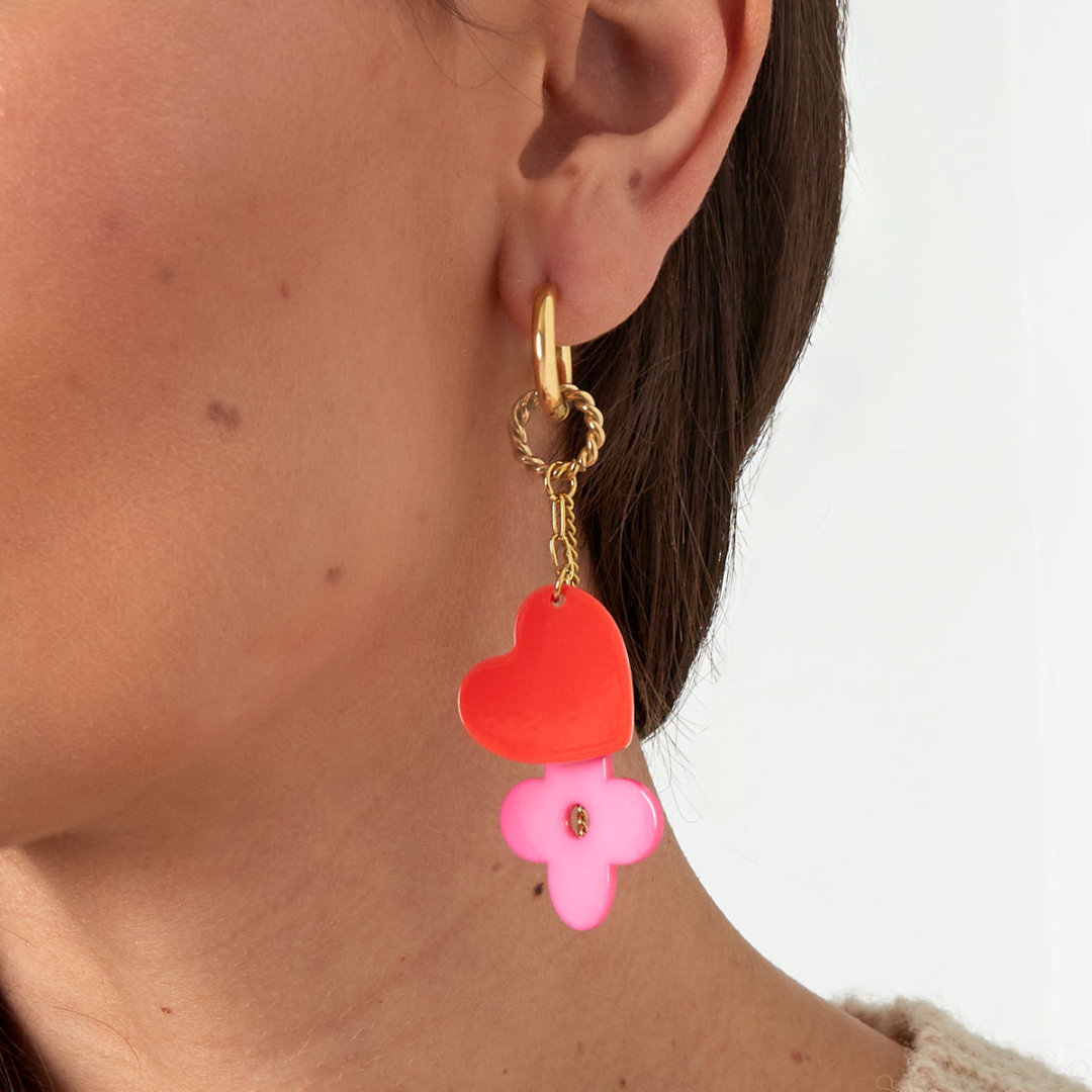 Créoles à breloques cœur et fleur colorées portées à l'oreille